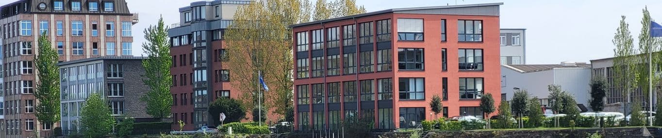 Bürogebäude am Wasser in Duisburg-Ruhrort, darunter das rote Gebäude der Kanzlei